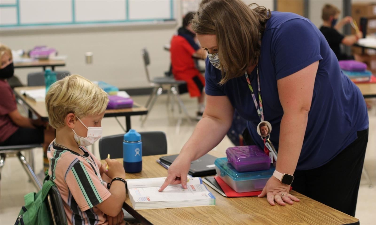 teacher helping student at desk 
